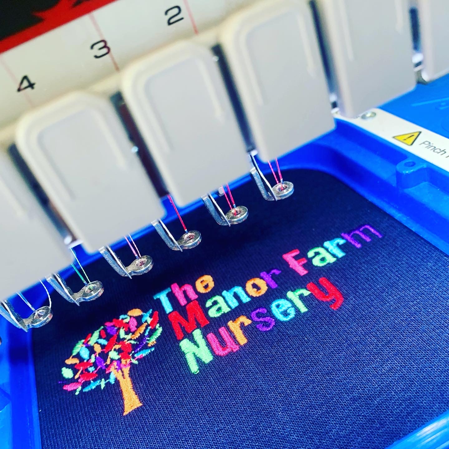 embroidery machine multicolour manor farm nursery logo on blue polo shirt
